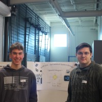 Two students standing next to a fourth karaoke project.